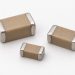 Three unbranded two-terminal MLCC ceramic capacitors arranged naturally on a white background