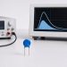 Metal oxide varistor beside a pulse generator and oscilloscope during an energy test