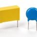 Unmarked yellow film capacitor and blue ceramic disc capacitor on a white background