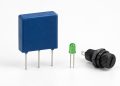Unbranded three-lead protected component beside a status LED and fuse holder on white